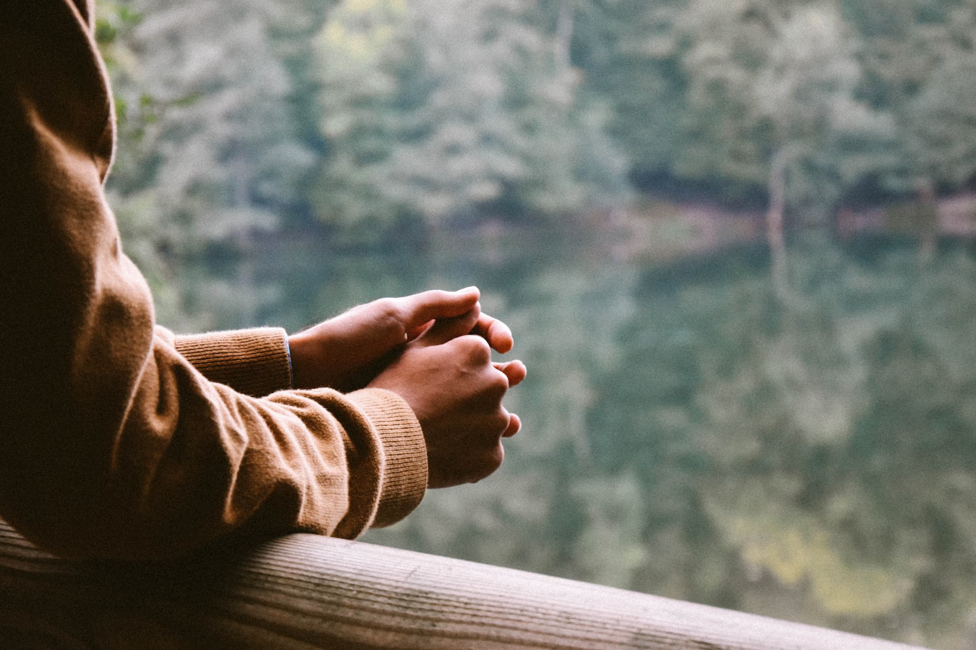 A person holding its own hands and gazing at the landscape